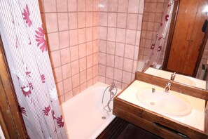 A bathroom with a bathtub, a wooden vanity, and a mirror.