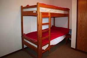 A bunk bed with a red mattress and white bedding.