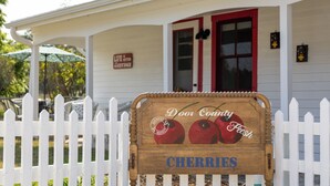 A wooden sign with a white picket fence in front of a house with a red door and a porch. - Charming Door County cottage steps from Lake Michigan Beach in Jacksonport WI (Sturgeon Bay)
