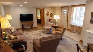 A living room with a sofa, armchairs, a TV, and a lamp. - Charming Door County cottage steps from Lake Michigan Beach in Jacksonport WI (Sturgeon Bay)