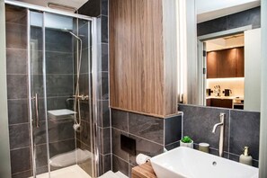 A modern bathroom with a glass-enclosed shower, a wooden vanity, and a large mirror. - The Mancunian Skyline | Chic 1BR City View w/ Wifi (Manchester)