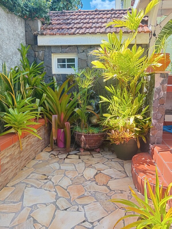 Un patio empedrado con plantas en macetas y un muro de piedra.