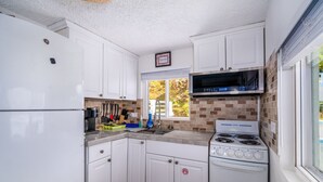 A compact kitchen with white cabinets, a built-in microwave, and a gas stove. - Seahorse Oceanfront Villa with Pool & Hot Tub! USVI (St Thomas)