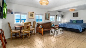 A room with a bed, a sofa, a dining table with chairs, and a small white table. - Seahorse Oceanfront Villa with Pool & Hot Tub! USVI (St Thomas)