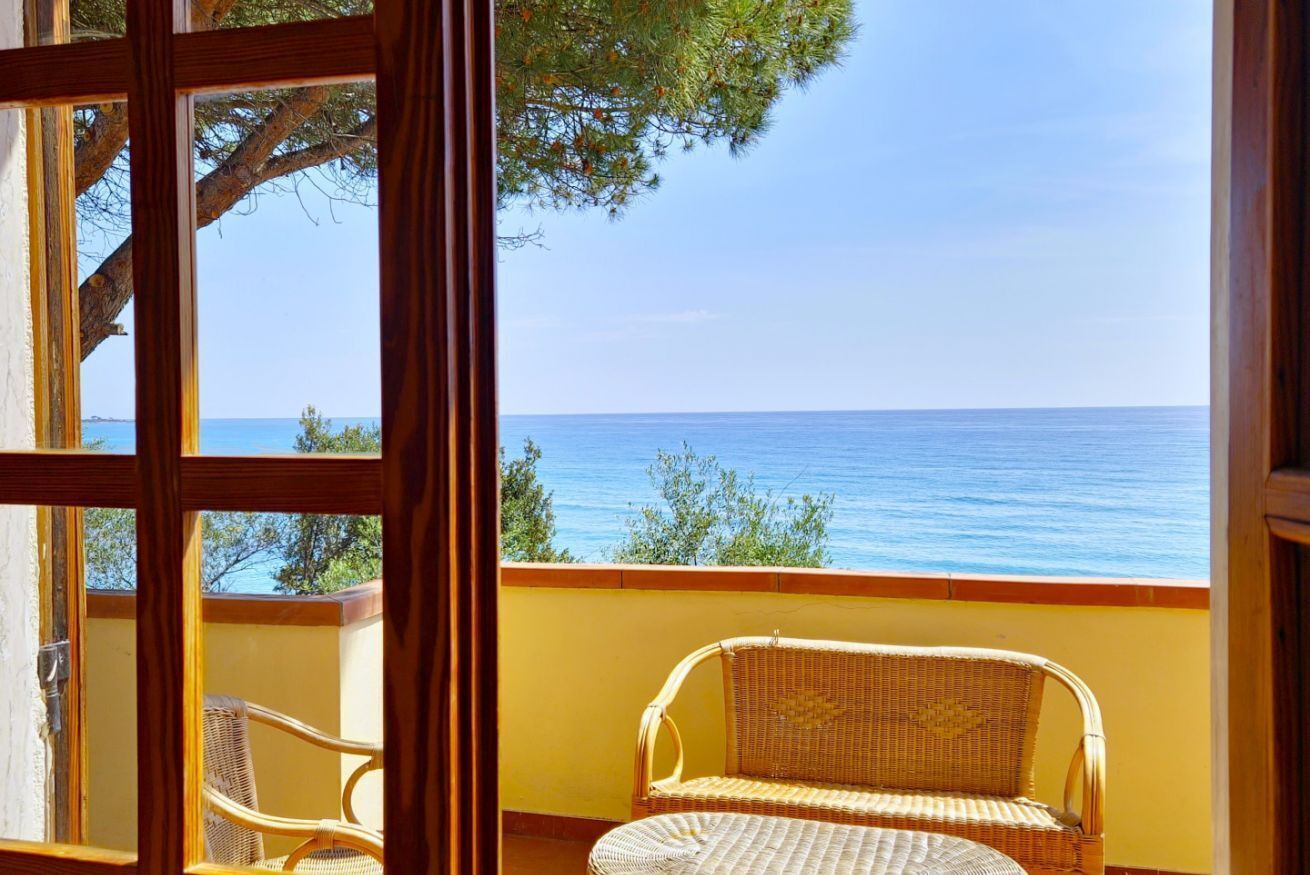 Ein Balkon mit einem Korbstuhl und Blick auf das Meer.