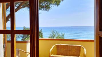 Ein Balkon mit einem Korbstuhl und Blick auf das Meer.