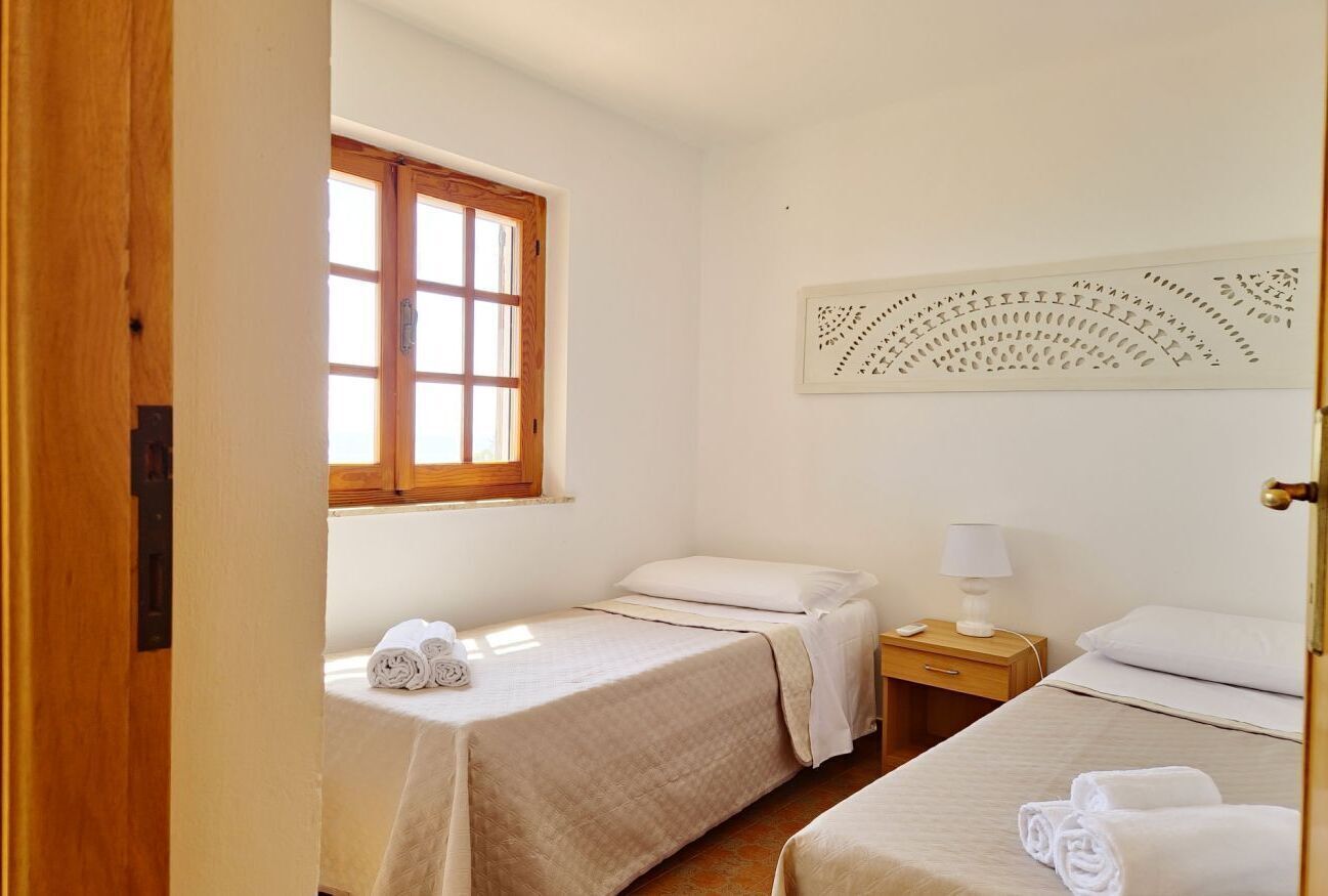A room with two single beds, a wooden door, a window, and a wall-mounted artwork.
