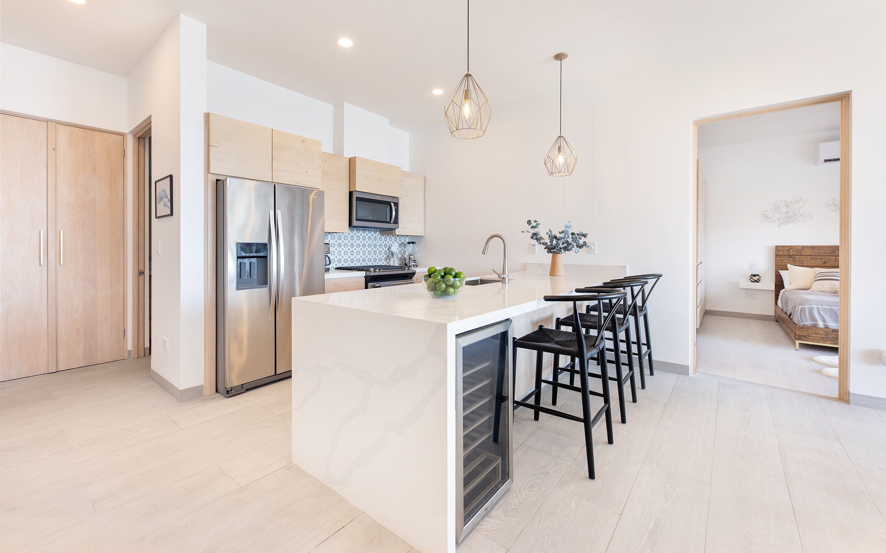 A modern kitchen with a central island, stainless steel appliances, and a dining area with black chairs.