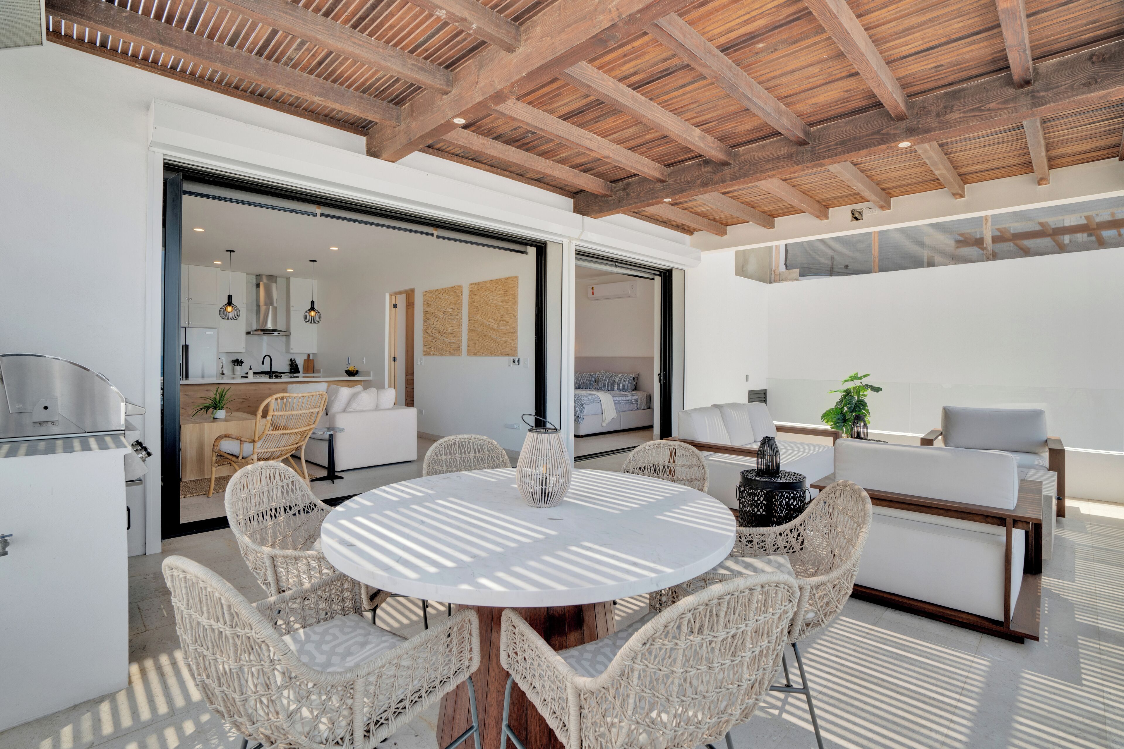 A modern outdoor dining area with wicker chairs, a round table, and a grill.