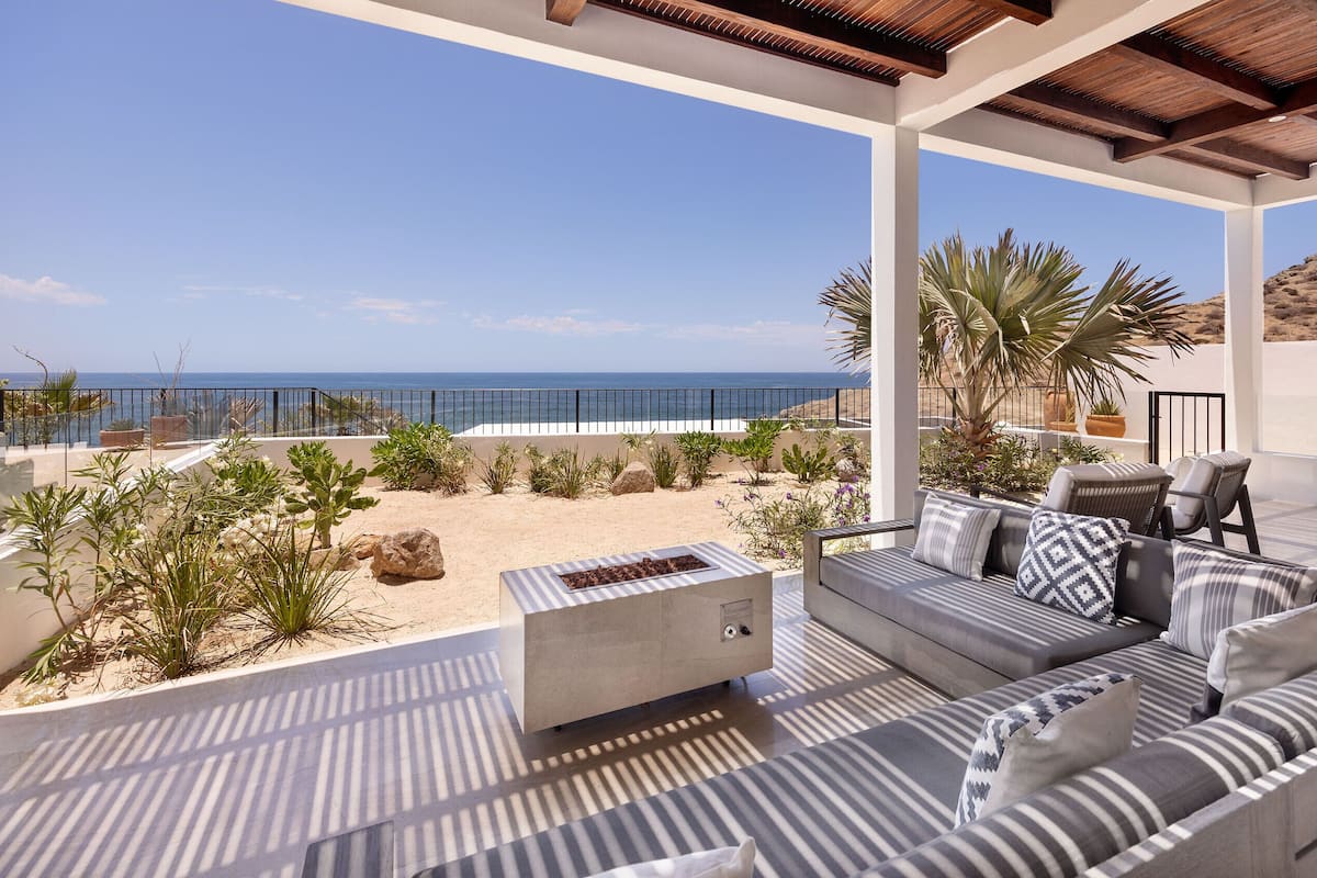 A covered outdoor seating area with a view of the beach and ocean.