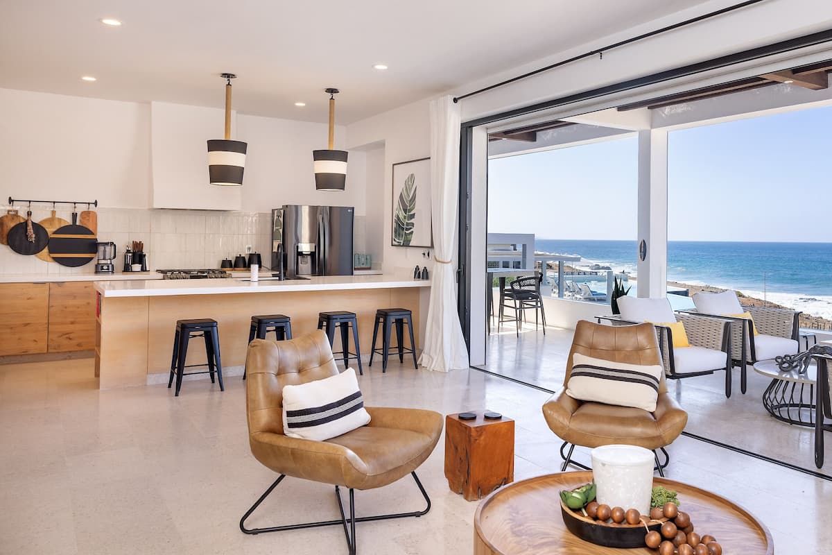 A modern kitchen with a large island, bar stools, and a view of the ocean.