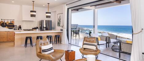A modern kitchen with a large island, bar stools, and a view of the ocean.