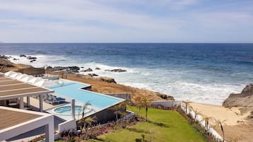 Un resort con piscina, sillas de descanso y vistas al océano.