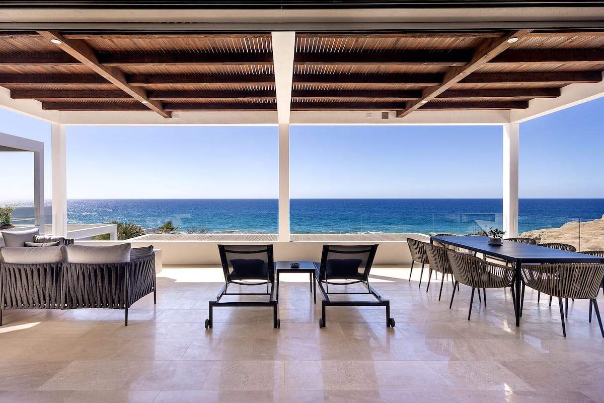 A terrace with a view of the sea, furnished with chairs and a table.