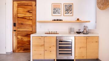 Une cuisine compacte avec des meubles en bois, un four encastré et une machine à café. Deux œuvres d’art encadrées sont accrochées au-dessus du plan de travail.