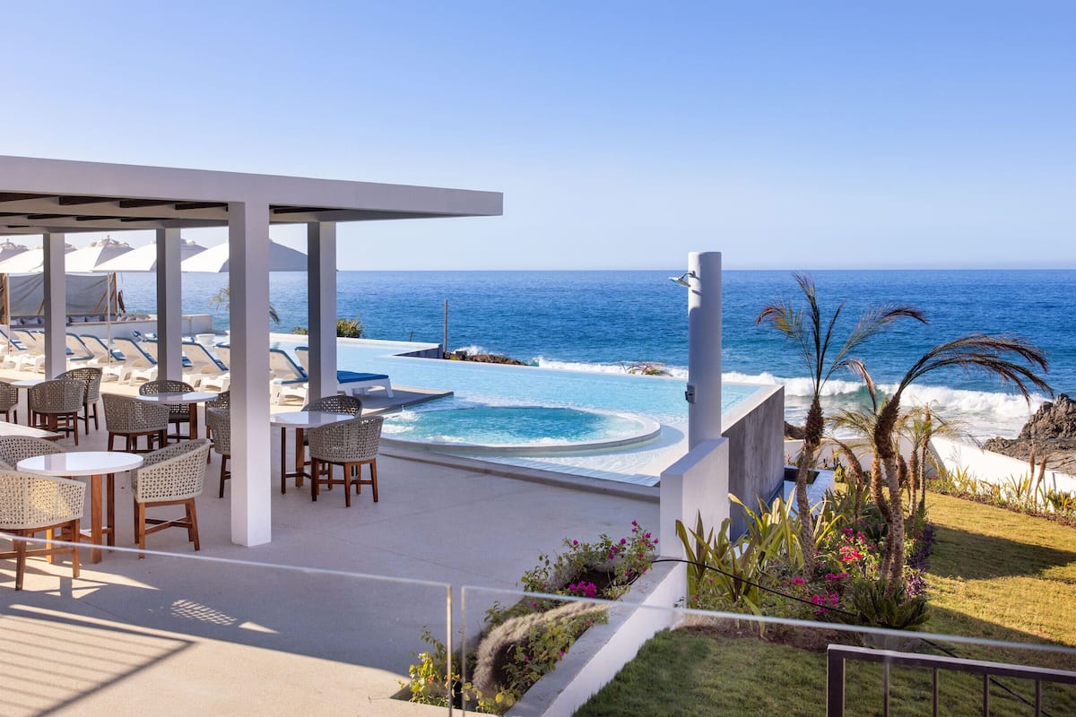 A rooftop bar with outdoor seating overlooking the ocean.