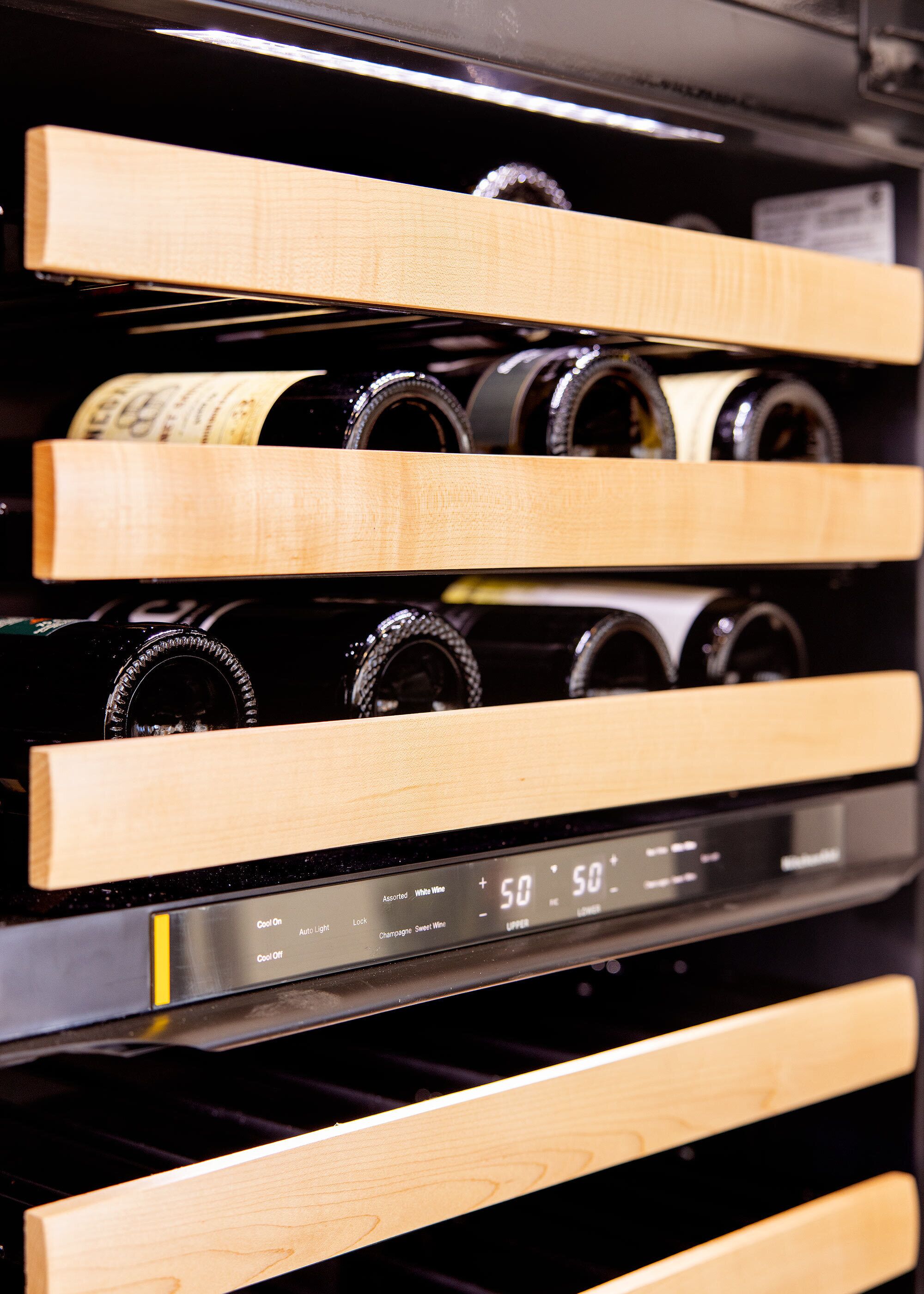 A wine rack with bottles and a digital temperature control display.