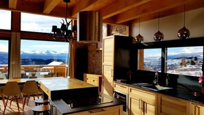 A modern kitchen with a large island, wooden cabinets, and a view of snowy mountains. - Chalet Louma Font-romeu Vue Panoramique Style Contemporain. 10 Couchages (Font-Romeu-Odeillo-Via)
