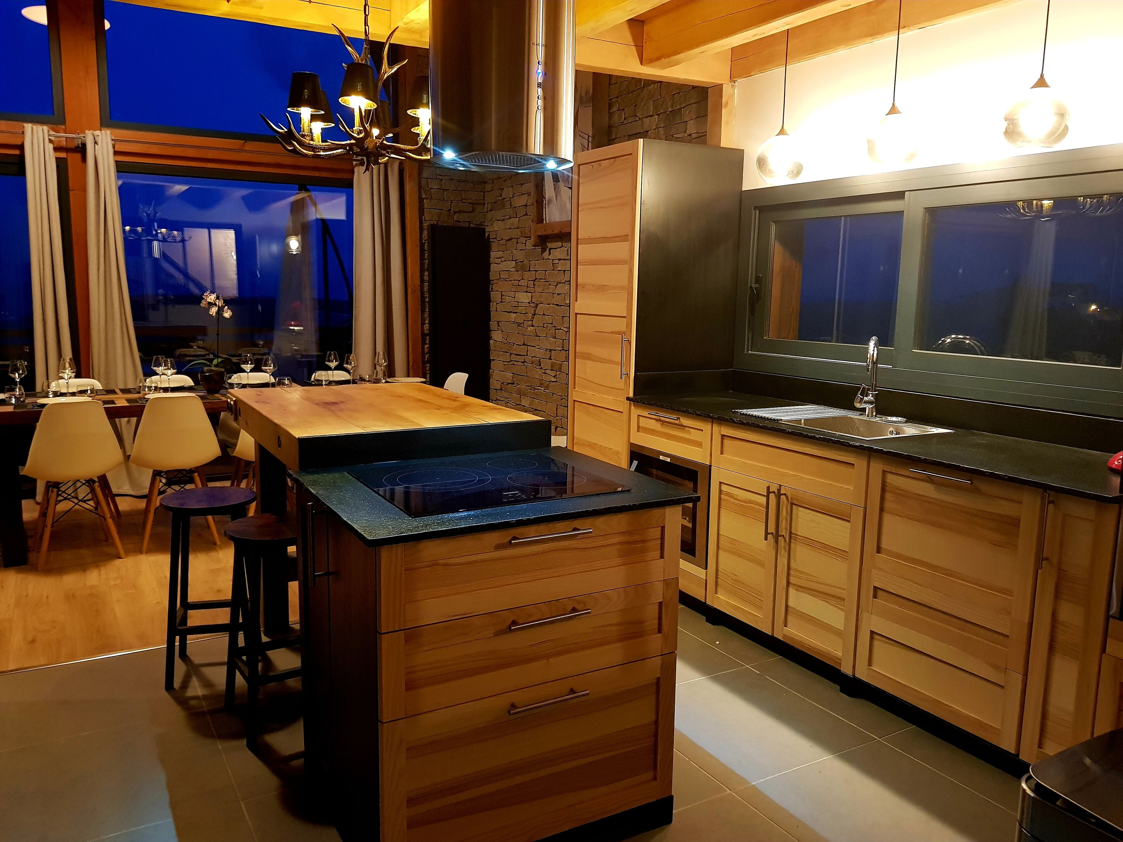 A modern kitchen with wooden cabinets, a black countertop, and a built-in stove.