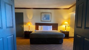 Ein Hotelzimmer mit einem großen Bett, zwei Nachttischen mit Lampen, einer Kopfteil und einem gerahmten Bild an der Wand.