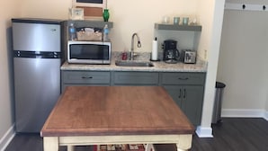 A kitchen with a wooden table, a refrigerator, a microwave, a sink, and a coffee maker. - Vineyard Villa overlooking 40 acres of Vineyards in Ohio Wine Country (Geneva)
