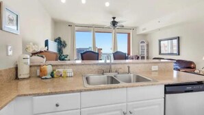 Una cocina con un lavamanos doble, armarios blancos y vistas a la ciudad a través de amplias ventanas.