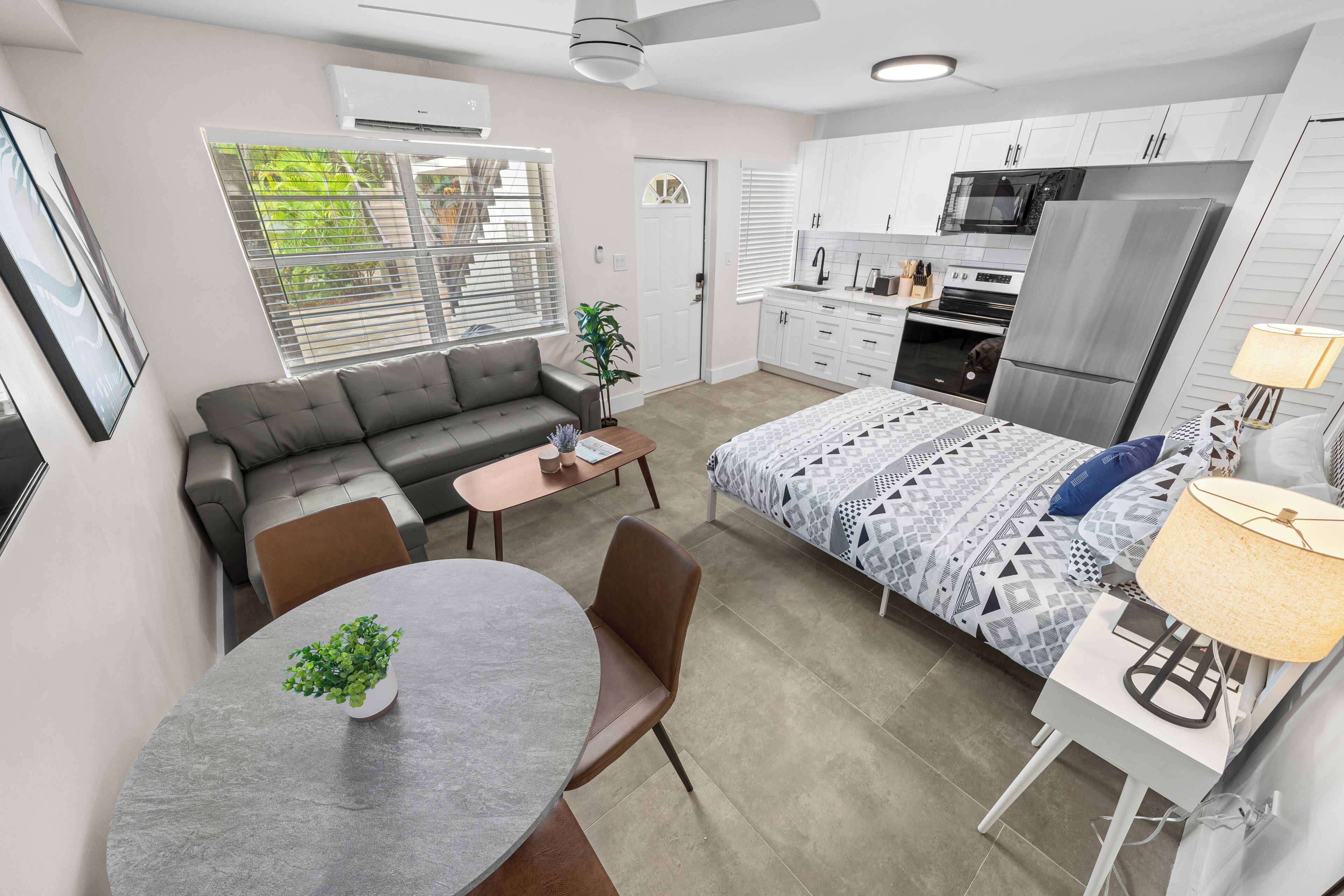 A modern kitchen with white cabinets, a stainless steel refrigerator, and a microwave.