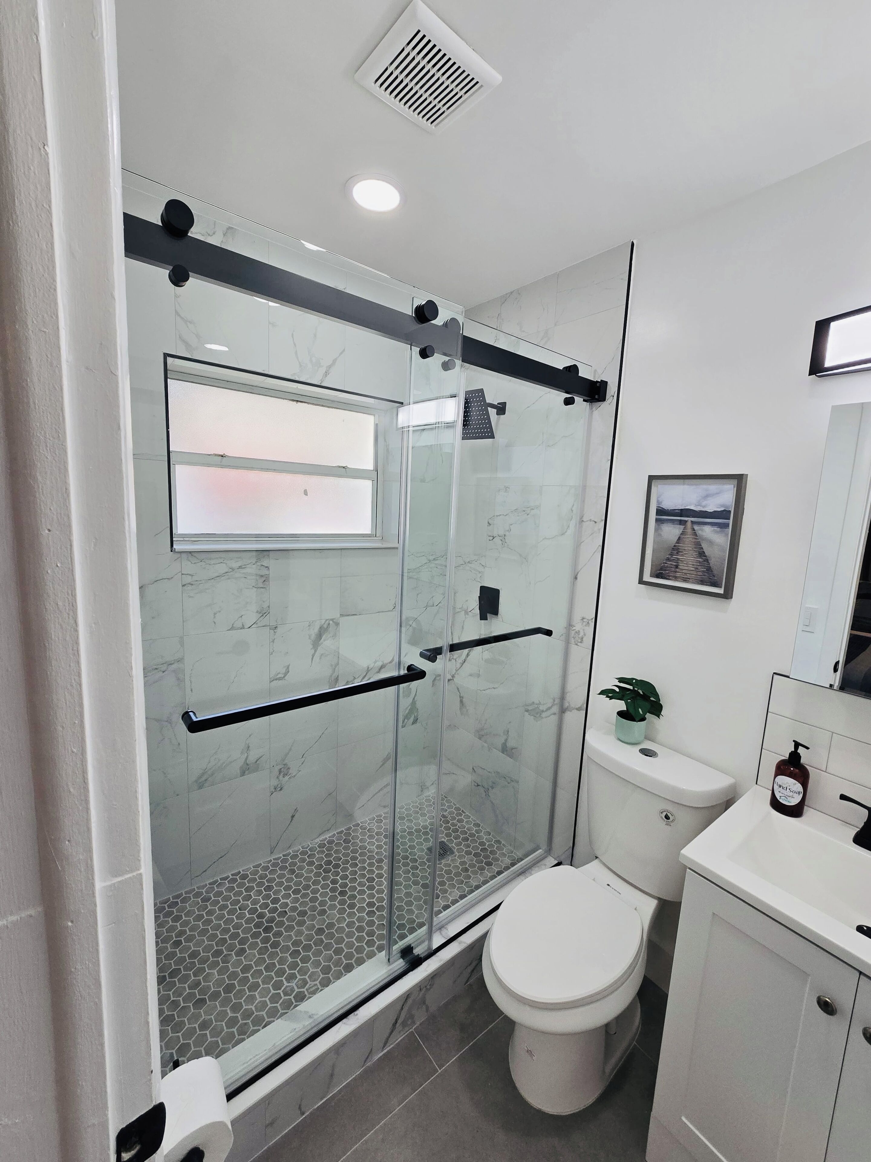 A modern bathroom with a glass-enclosed shower, a toilet, and a sink.