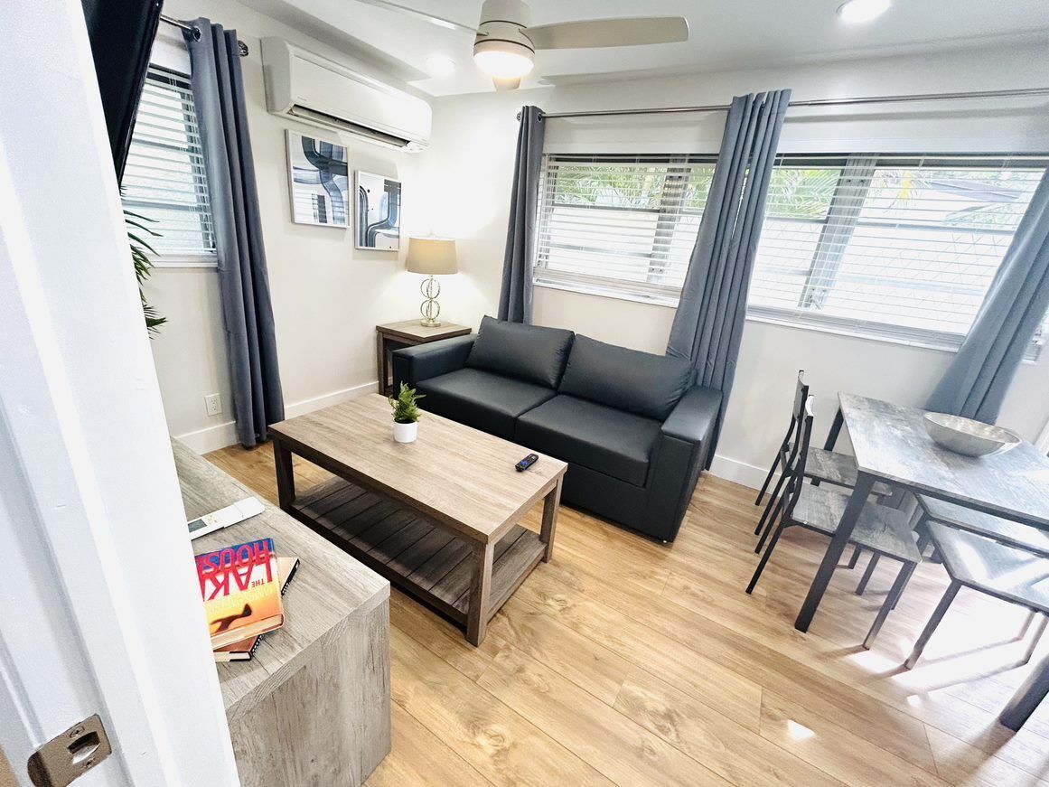 A modern living room with a sofa, coffee table, and dining area.