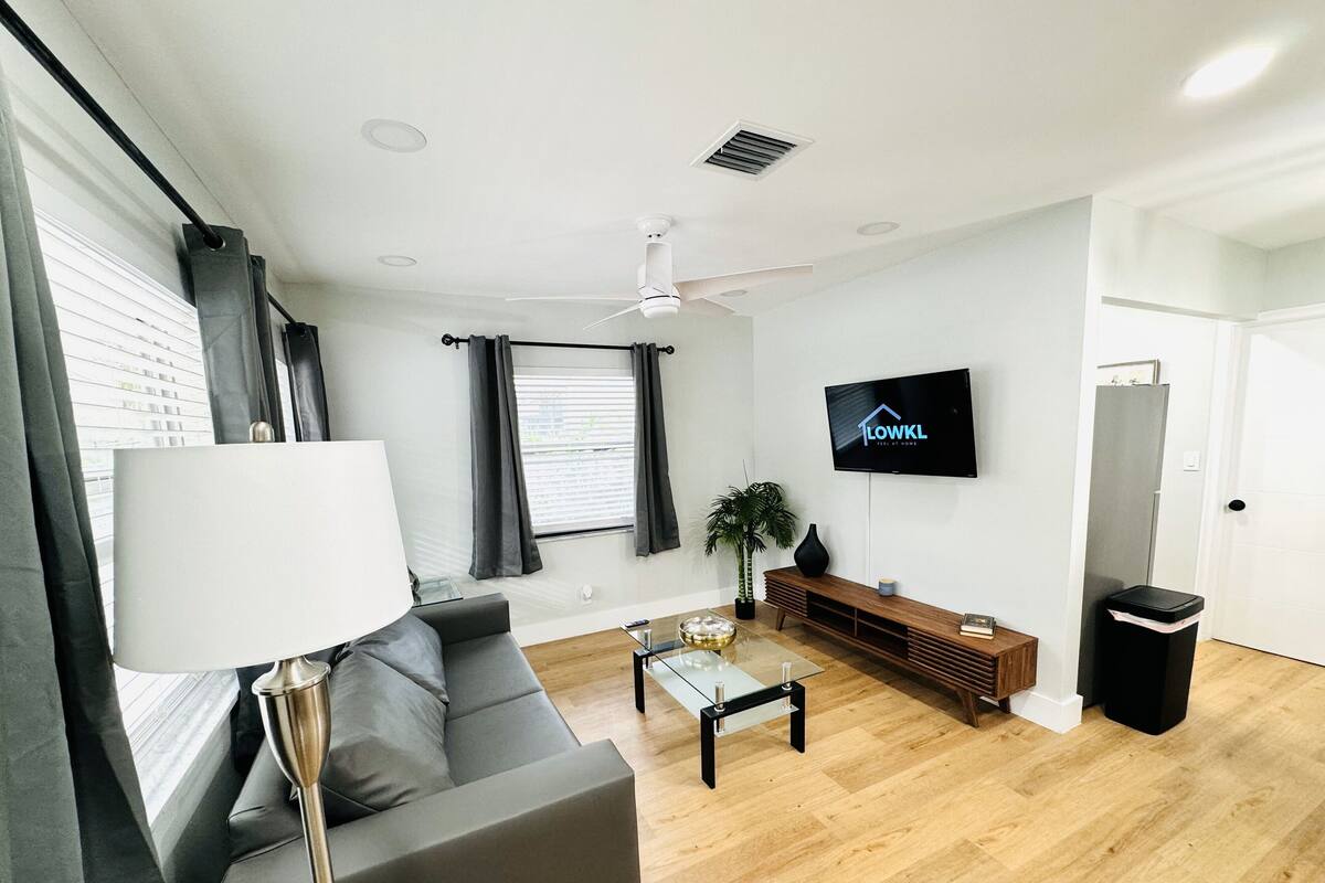 Ein modernes Wohnzimmer mit einer Couch, einem Couchtisch, einem Fernseher und einem Deckenventilator.