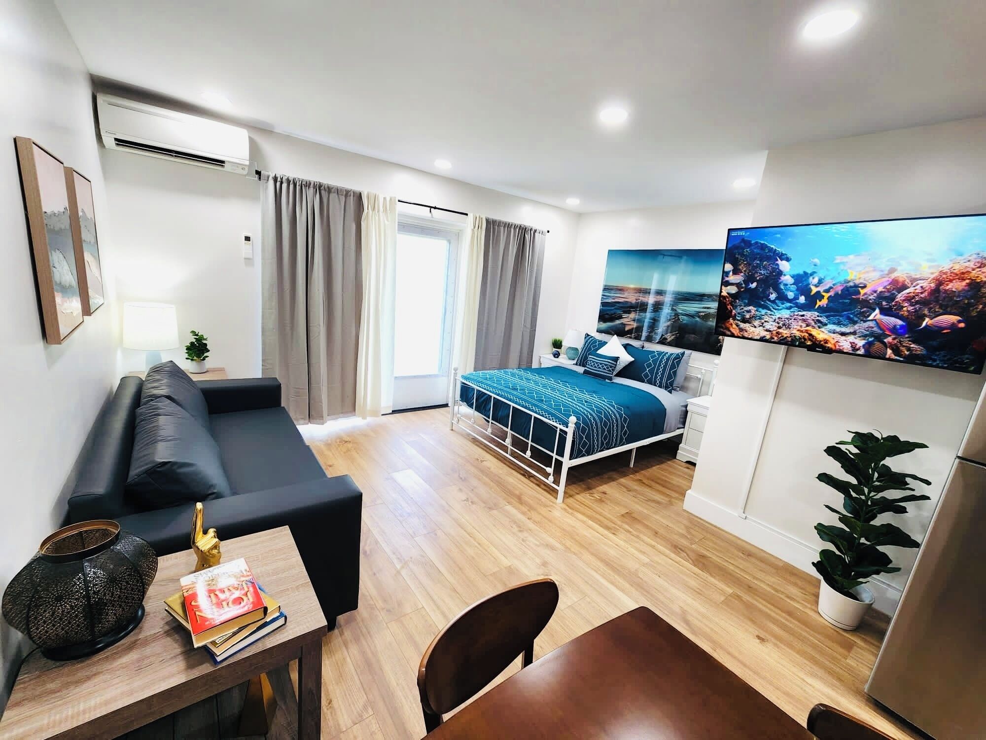 Ein modernes Schlafzimmer mit Bett, Sofa, Schreibtisch und Fernseher.
