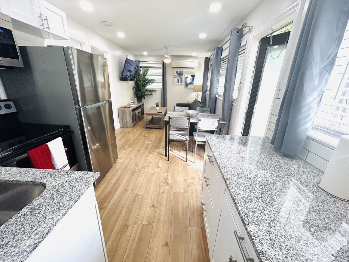 A modern kitchen with granite countertops, stainless steel appliances, and wooden flooring.