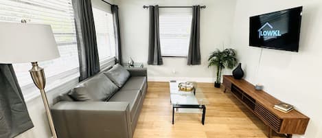 A modern living room with a grey sofa, a coffee table, a TV, and a ceiling fan.