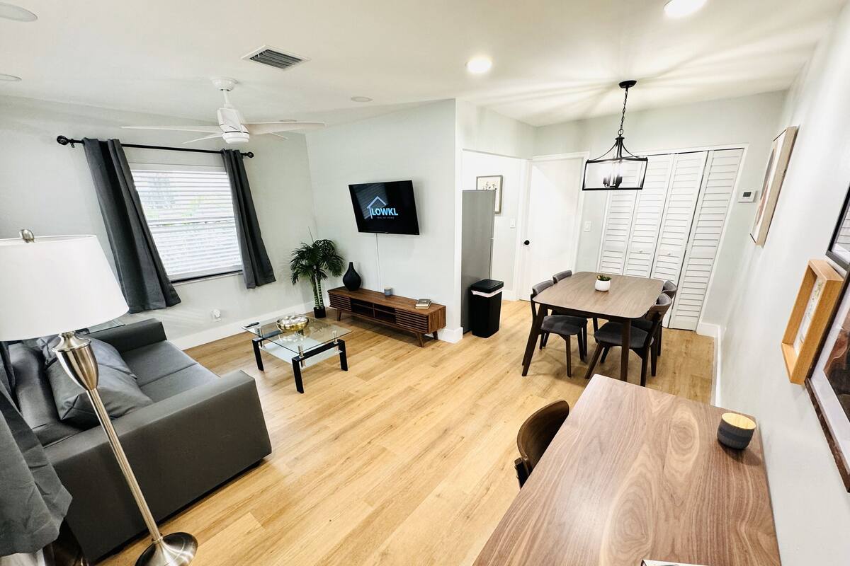 Ein modernes Wohnzimmer mit einer Couch, Couchtisch, Fernseher und Essbereich.