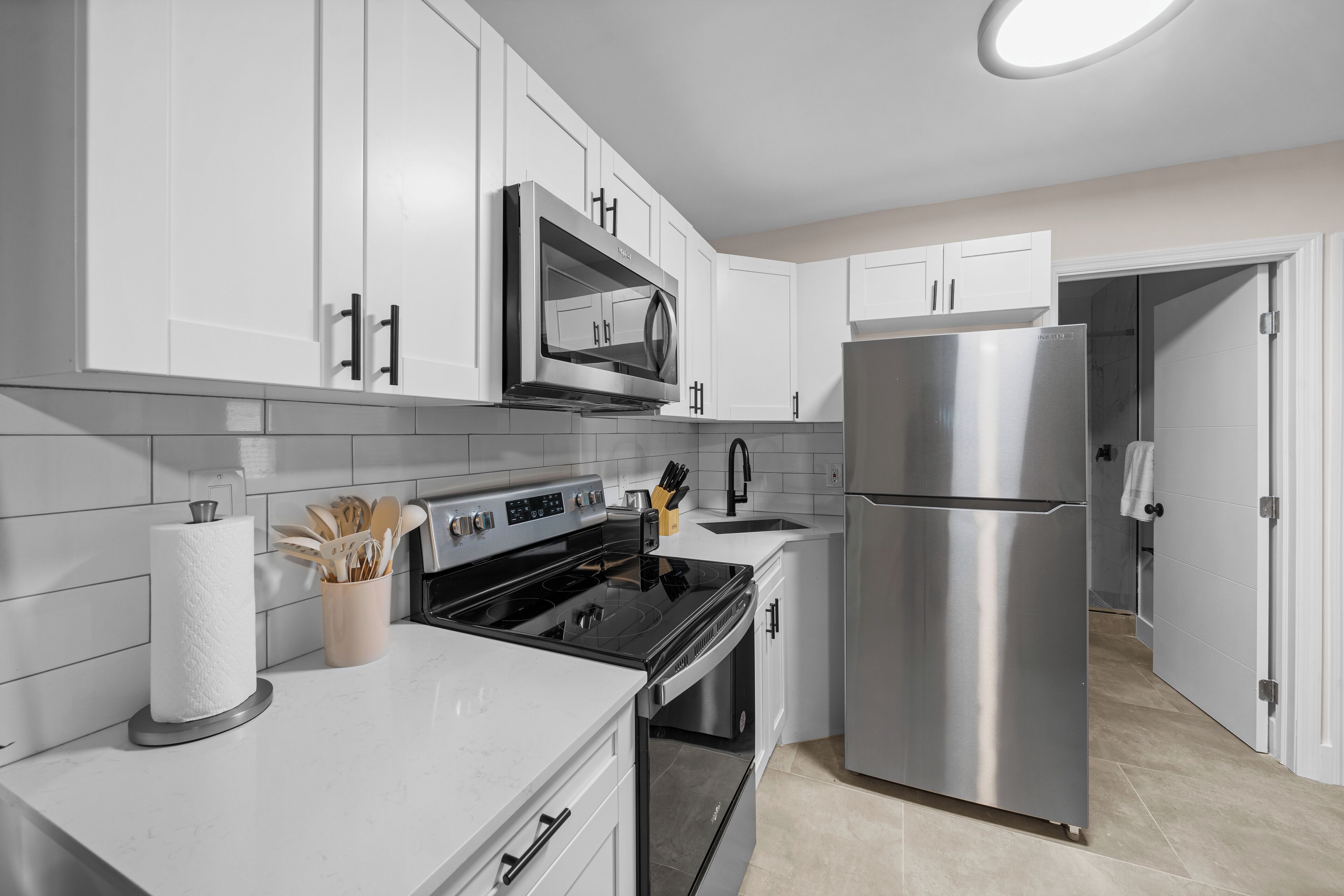 A modern kitchen with white cabinetry, stainless steel appliances, and a tiled backsplash.
