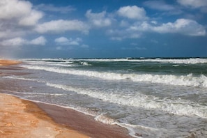 A beach with waves crashing onto the shore under a partly cloudy sky. - Daytona Bike Week March 5 - March 12, 2027 (Ormond Beach)