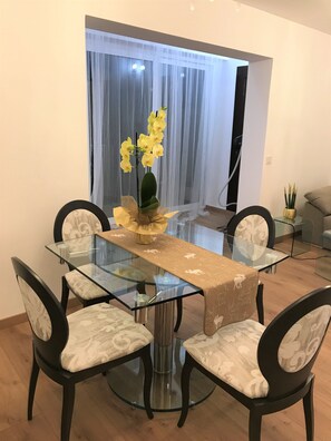 Enjoy meals in this stylish dining area with a glass-top table, beige runner, and elegant centerpiece.