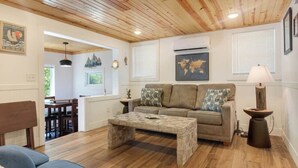 A living room with a wooden ceiling, a sofa, a coffee table, and a lamp.