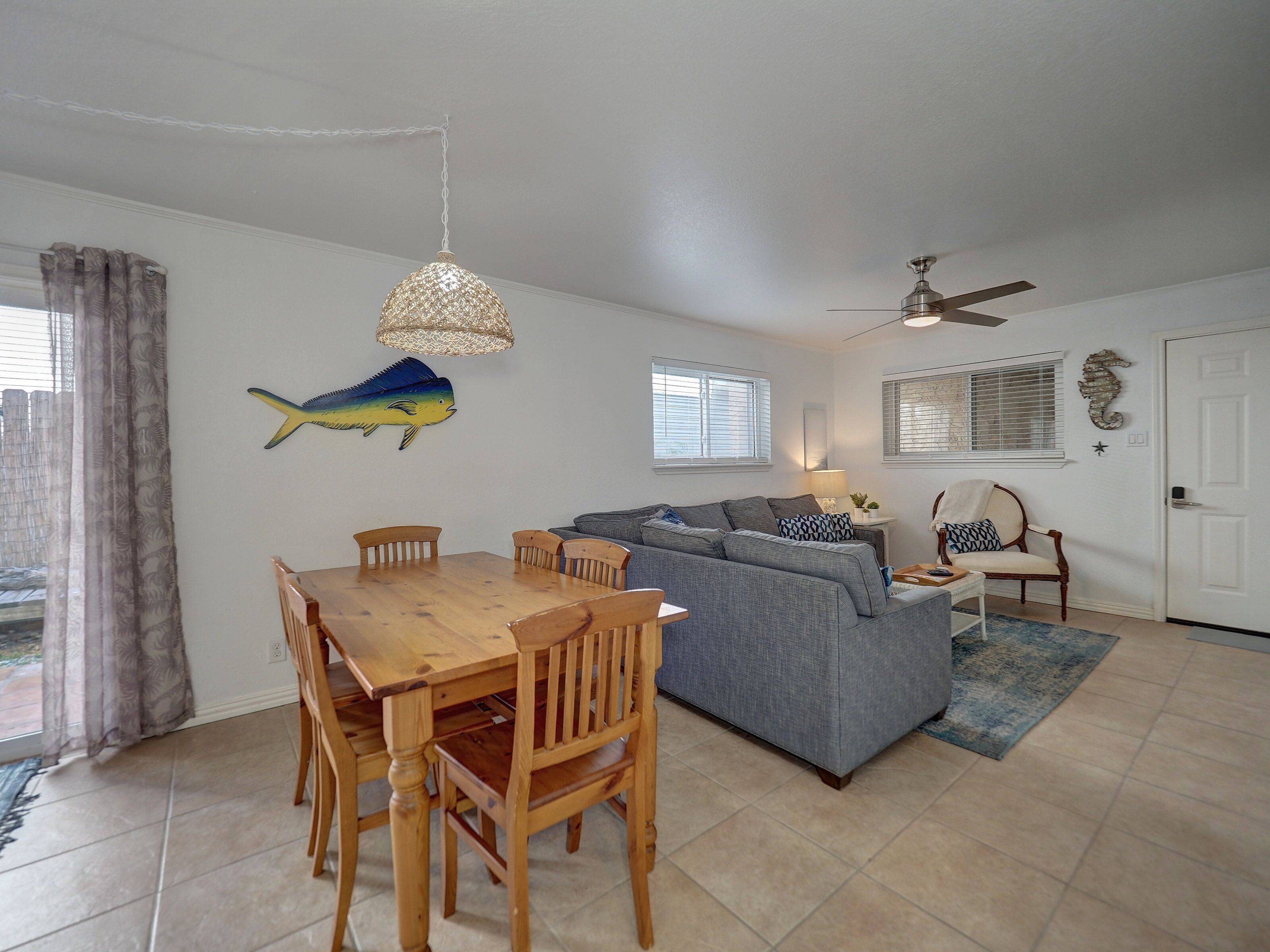 A living room with a dining table, sofas, and a ceiling fan.
