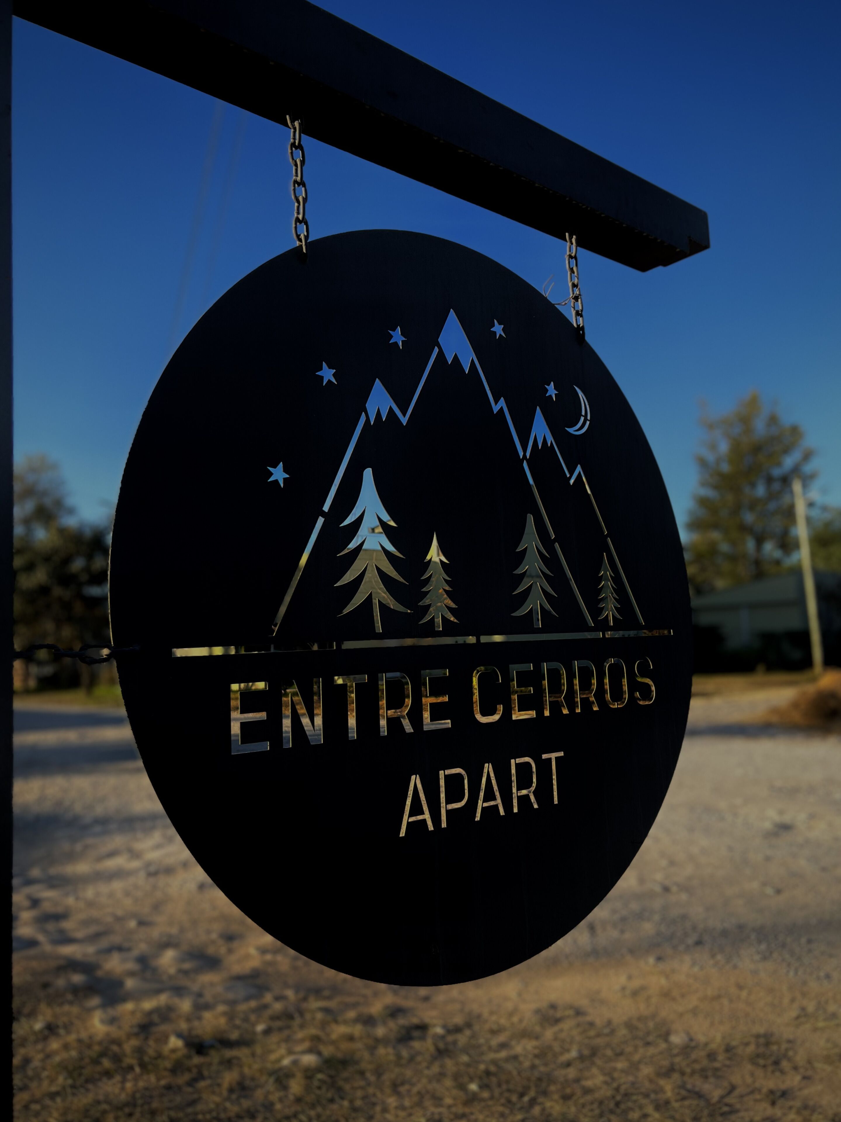 A sign with a mountain and tree design, and the text "ENTRE CERROS APART".