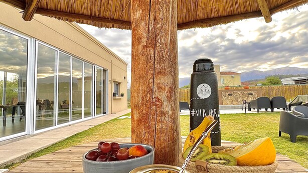 An outdoor dining area with a thatched roof, a large water dispenser, and a fruit bowl. - Entre Cerros Apart (Salta)