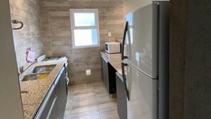 A modern kitchen with a stainless steel refrigerator, a microwave, and a sink. - Entre Cerros Apart (Salta)