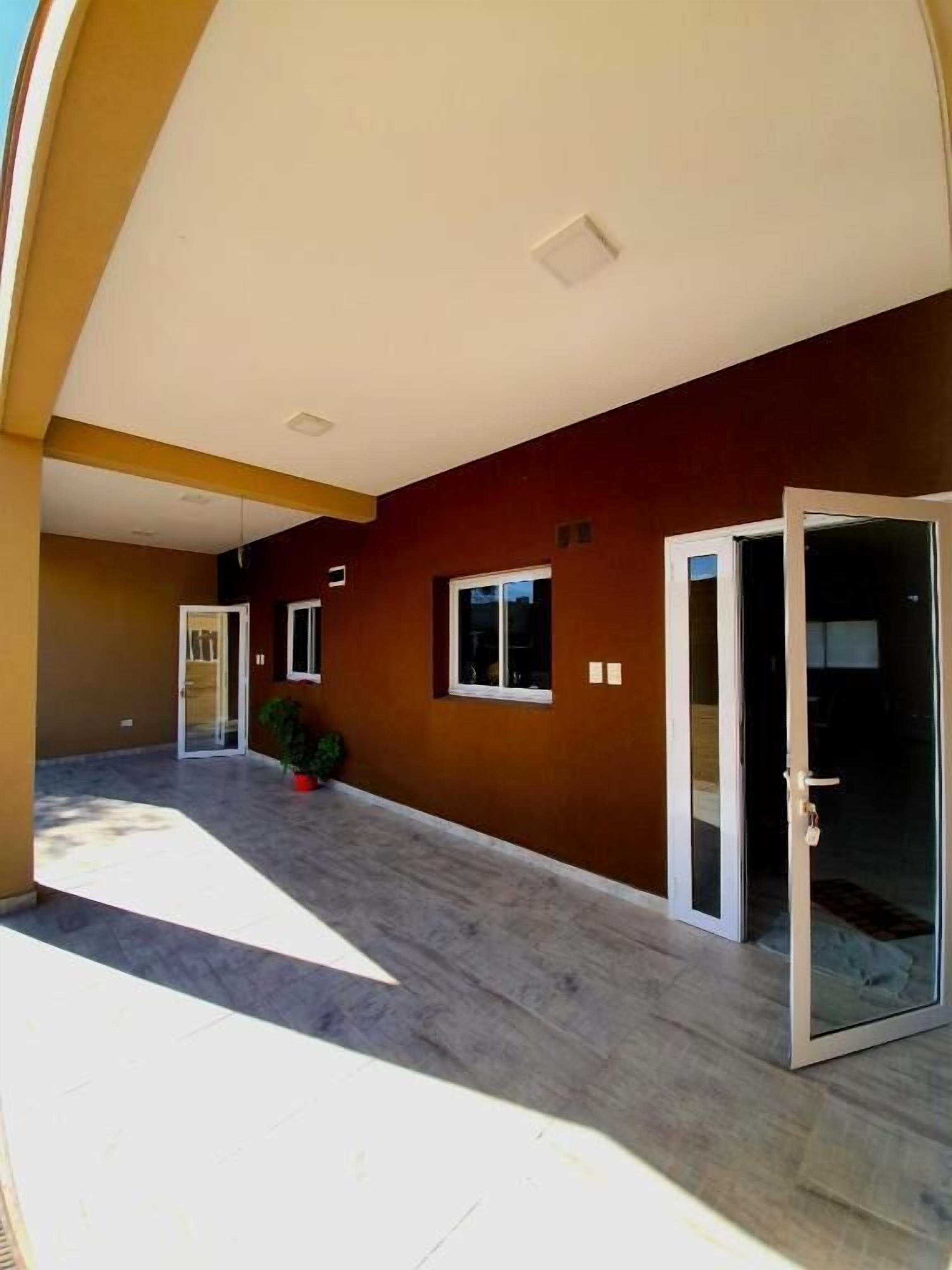 A spacious outdoor area with a covered patio, a door leading to a covered entrance, and a small window.