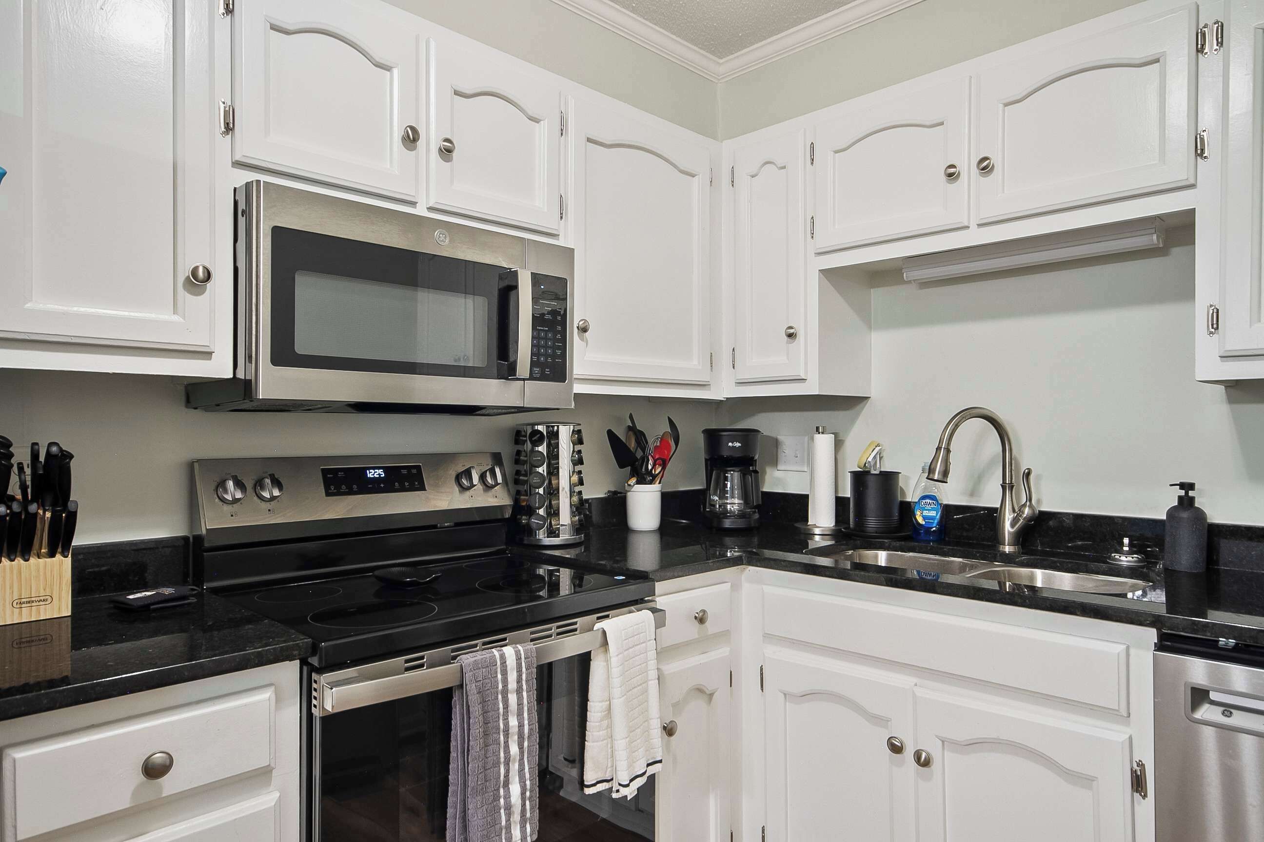 Una cocina moderna con armarios blancos, electrodomésticos de acero inoxidable y encimeras negras.