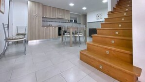 Eine moderne Küche mit Holzausstattung, ein Essbereich mit zwei Stühlen und eine Treppe.