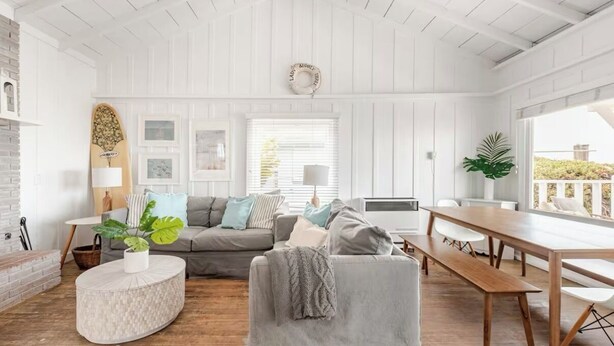 A cozy living room with a grey sofa, a round coffee table, and a wooden dining table. - Carpinteria Beach Front Bungalow  (Carpinteria)