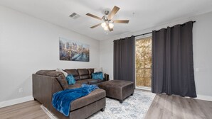 Ein modernes Wohnzimmer mit einem braunen Ledersofa, einer blauen Decke und einem Stadtbild an der Wand.