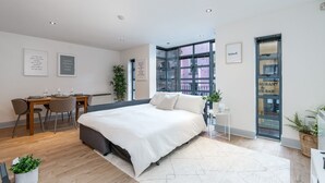 Une chambre moderne avec un grand lit, un bureau et une fenêtre donnant sur un immeuble.
