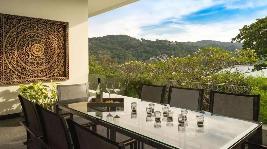 Une table à manger avec des chaises, un élément décoratif mural et une vue sur un lac et des collines.