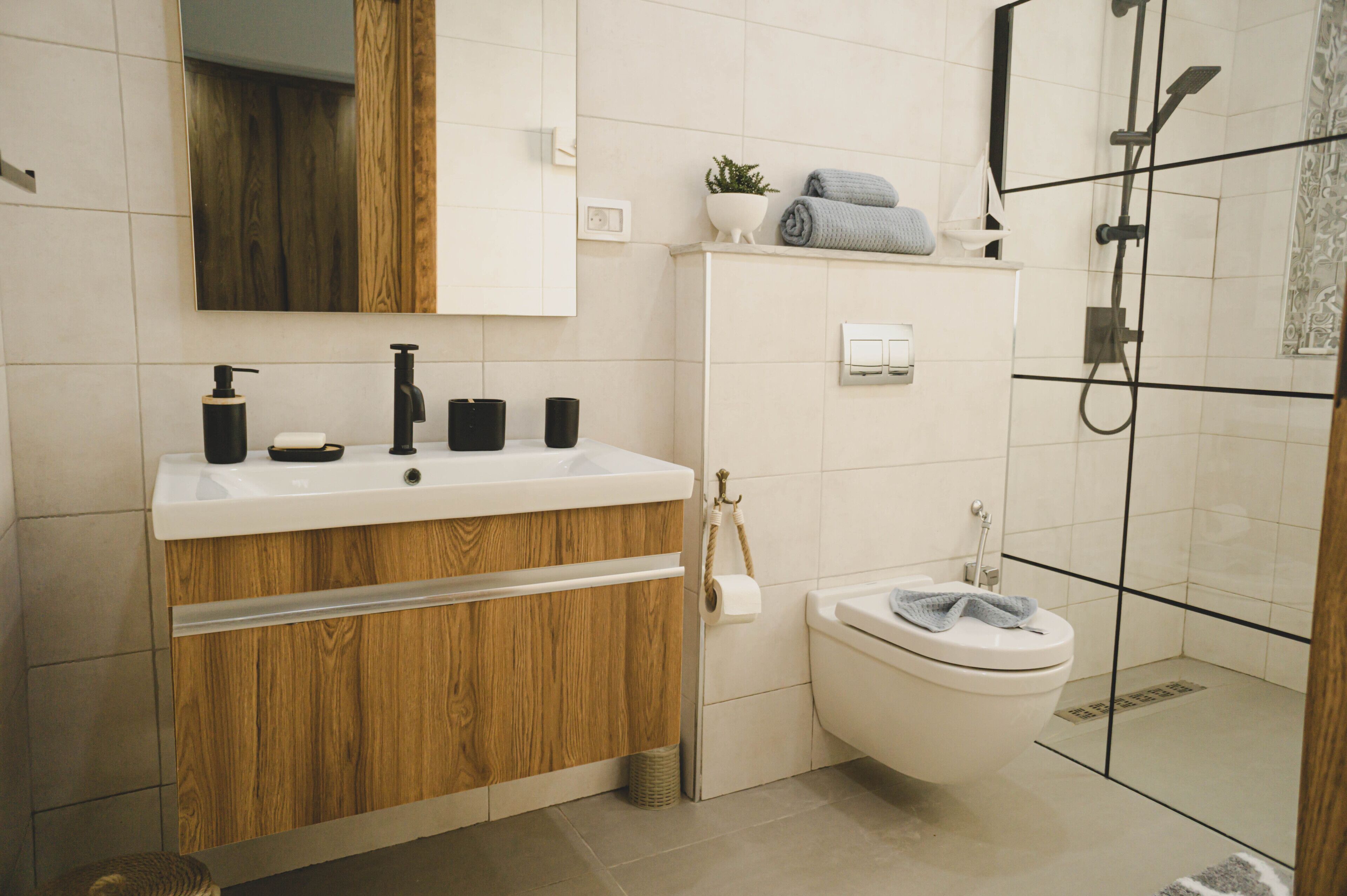 Un baño moderno con tocador de madera, inodoro, ducha y espejo.